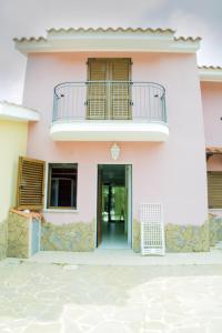 ein rosafarbenes Haus mit einem Balkon und einer Tür in der Unterkunft Villa Gabriella in Porto Pino