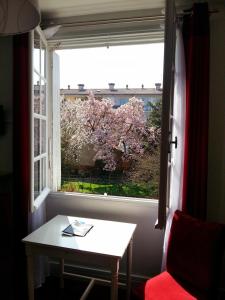 ein Fenster mit einem Tisch und einem Baum mit rosa Blumen in der Unterkunft Hôtel La Résidence in Villeneuve-sur-Lot