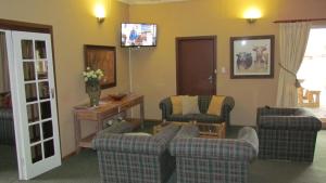 ein Wohnzimmer mit Sofas und einem TV an der Wand in der Unterkunft Wagon Wheel Country Lodge in Beaufort West