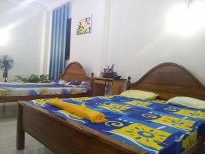 1 Schlafzimmer mit 2 Betten mit einer blauen und gelben Tagesdecke in der Unterkunft Aruliya Ayurveda Resort Galle in Galle