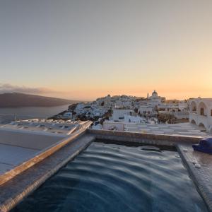 a swimming pool on the roof of a building with a city at Enalion White Suites Oia in Oia