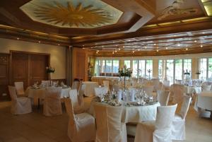 um salão de banquetes com mesas brancas e cadeiras brancas em Hotel Jägerhof em Weibersbrunn