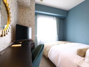 a bedroom with a bed and a television on a table at KOKO HOTEL Osaka Umeda in Osaka