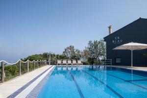 einem Pool mit Stühlen und einem Sonnenschirm neben einem Gebäude in der Unterkunft Hotel Es Blau Des Nord in Colònia de Sant Pere