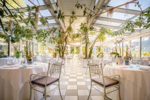 un salón de banquetes con mesas, sillas y plantas en Villa Tivoli, en Merano