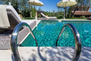 a swimming pool with two chairs and an umbrella at Villa Ligheia in Gambassi Terme