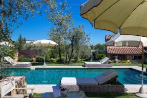 a swimming pool with chairs and an umbrella at Villa Ligheia in Gambassi Terme