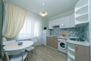 eine Küche mit einem Tisch, einem Waschbecken und einer Waschmaschine in der Unterkunft Софии Русовой 7 in Kiew