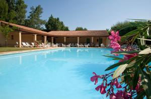 uma piscina com cadeiras e flores em frente a uma casa em Le Mas Des Sables em Aigues-Mortes