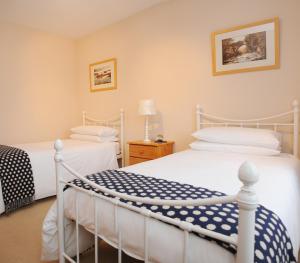 a bedroom with two white beds and a lamp at Cottesmore Bed and Breakfast in Bushmills