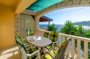 a table and chairs on a balcony with the ocean at Apartments Ranko in Zavalatica