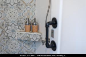 a bathroom with three toothbrushes on a shelf at Sawatdee Guesthouse the Original in Bangkok