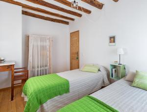 2 camas en una habitación blanca con sábanas verdes en Casa Les Germanes, en Gramuntell