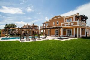 a large house with a yard with chairs and a pool at Colina da Lapa & Villas in Carvoeiro