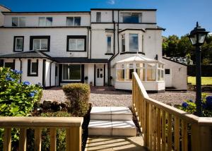 ein großes weißes Haus mit einer Veranda und einem Zaun in der Unterkunft Lochside Guest House in Arrochar