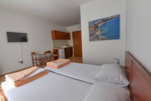 a bedroom with a large white bed and a kitchen at Studio Apartments 6 Palmi in Budva