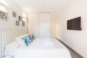 マルベーリャにあるSeaside Marbella Apartmentsの白いベッドルーム(白いベッド1台、薄型テレビ付)