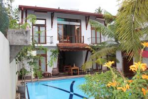 a villa with a swimming pool in front of a house at Villa Kapuru in Negombo