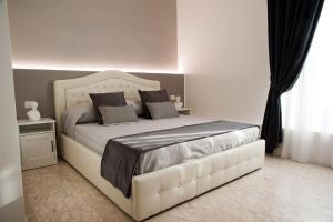 una camera da letto con un grande letto bianco con cuscini di Lifestyle Veneto Suite a Roma