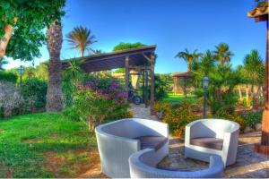 a garden with two white chairs and a gazebo at I Giardini di San Vito lo Capo in San Vito lo Capo