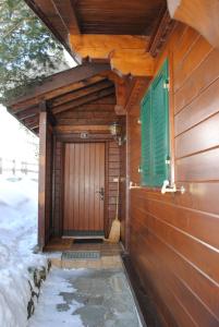 a front door of a wooden house with a green shutter at Apartment Nadeschda in Adelboden