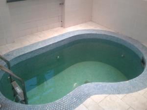 a bath tub with green water in a bathroom at Kolos Hotel Obolon in Kyiv