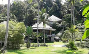 a house in the middle of a garden with palm trees at Beachfront TalingNgam in Taling Ngam Beach