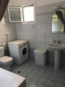 a bathroom with a toilet a sink and a washing machine at Cosy 3bedroom Apartment in Sami +12 photos