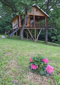 a tree house with a deck and some pink flowers at Treehouse Resnice -Mrežnica in Barilović