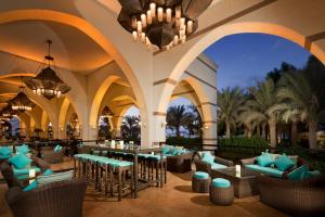 迪拜Jumeirah Zabeel Saray Dubai的度假村大堂设有桌椅和吊灯。