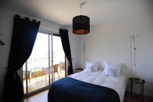 a bedroom with a bed and a window with a balcony at T2 Terrasse Vue Mer - Route des Sanguinaires in Ajaccio