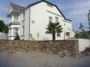 a white house with a brick wall and a palm tree at Drakewalls Bed And Breakfast in Gunnislake