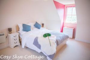 a bedroom with a white bed with a green plant on it at Cosy Skye Cottage in Kingsburgh