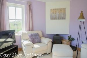 a living room with a chair and a tv at Cosy Skye Cottage in Kingsburgh