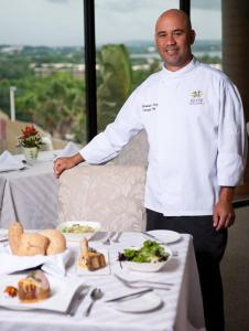 a chef standing next to a table with food on it at Mayaguez Resort & Casino in Mayaguez
