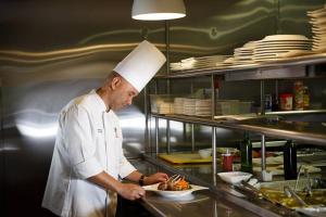a chef in a kitchen holding a plate of food at Mayaguez Resort & Casino in Mayaguez