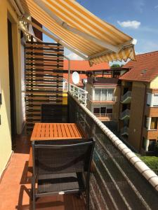 a balcony with a wooden table and a bench at Lilly in Siófok