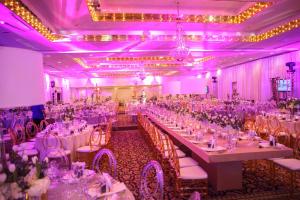 un salón de banquetes con mesas y sillas blancas e iluminación púrpura en Mayaguez Resort & Casino, en Mayagüez