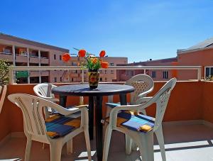 stół z krzesłami i wazon z kwiatami na balkonie w obiekcie MARINEDA by RENTMEDANO newly renovated, ocean view, wifi, parking, pool w mieście El Médano
