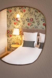 a white bed with white sheets and a mirror at Hotel Edouard VII in Biarritz