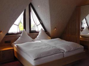 a bed in a room with three windows at Landhaus Schneider in Sasbachwalden
