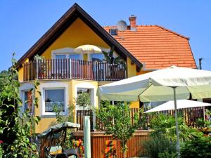 ein gelbes Haus mit Balkon und Sonnenschirm in der Unterkunft Villa Schwalbennest in Vonyarcvashegy
