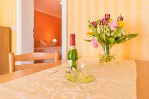 una bottiglia di vino e un vaso di fiori su un tavolo di Haus Mozart a Binz