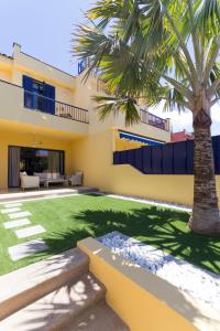 a house with a palm tree in the middle of a yard at Fantastico Duplex en Meloneras in Meloneras