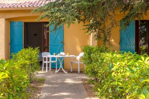 una mesa y sillas en el porche de una casa con puertas azules en Azureva Argeles en Argelès-sur-Mer