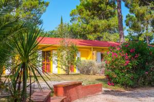 una casa amarilla con techo rojo y algunas flores en Azureva Argeles en Argelès-sur-Mer