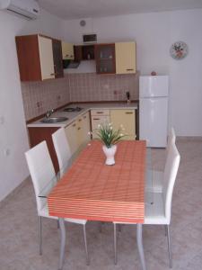 cocina con mesa, sillas y nevera en Apartments Nives, en Supetar