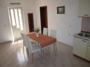 cocina con mesa de madera y sillas blancas en Apartments Nives, en Supetar