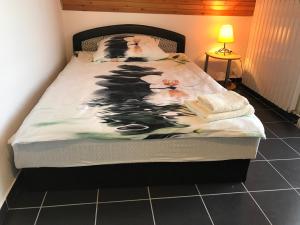 uma cama com um cobertor preto e branco em Orchidea Vendégház - Zebegény em Zebegény