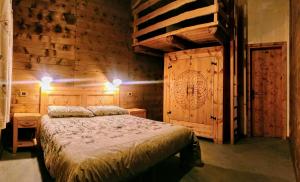 a bedroom with a bed and a wooden wall at Delfin Dal Pianhol in Casteldelfino